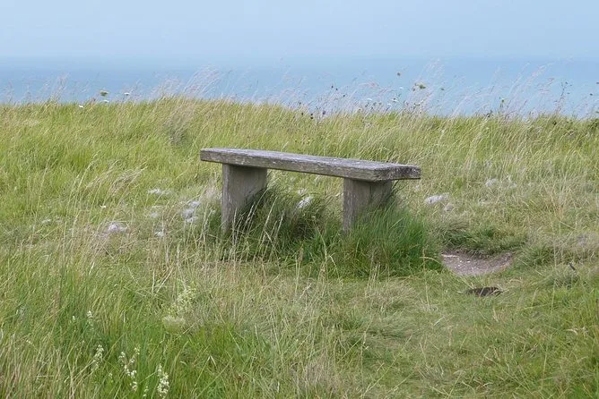 Eine Holzbank auf der grasbewachsenen Klippe über dem Meer bei Dover